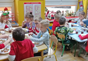 Dzieci degustują samodzielnie udekorowane pierniczki, popijając owocową herbatke z miodem